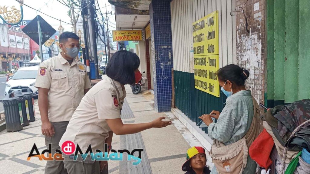 Petugas Satpol PP Kota Malang memberikan masker kepada masyarakat yang tidak memakai masker saat berada di Kayutangan Heritage (Foto : Agus Yuwono ~ AdaDiMalang.com)