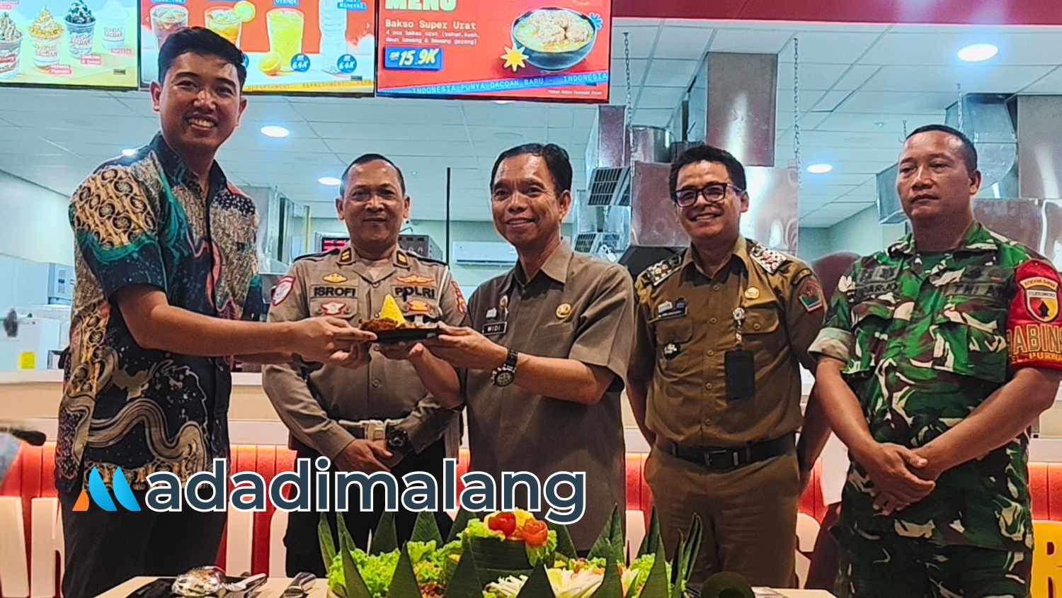 Camat Blimbing kota Malang,Widi, saat menyerahkan potongan tumpeng kepada Head of Business Development & Operation Bakso Gacoan, Brian Hutama sebagai simbolis peresmian gerai Bakso Gacoan di Malang (Foto : Agus Yuwono)